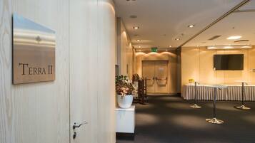 Un vestíbulo de hotel con mostrador de recepción, un letrero que dice "Terra II" y una zona de estar con mesas y sillas.