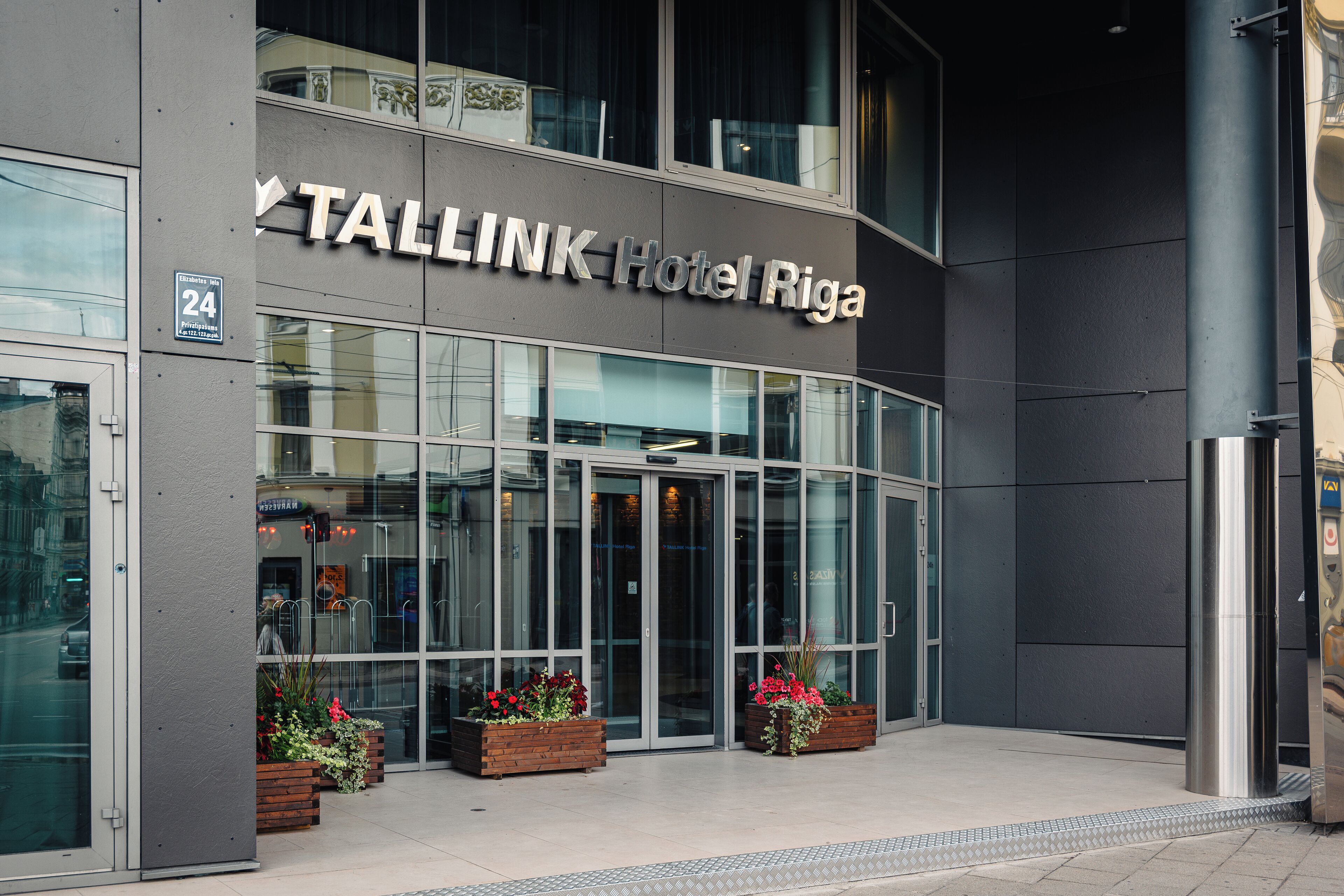 L’extérieur de l’hôtel Tallink de Riga se distingue par sa façade moderne, son grand hall d’entrée vitré et les jardinières fleuries qui l’ornent.