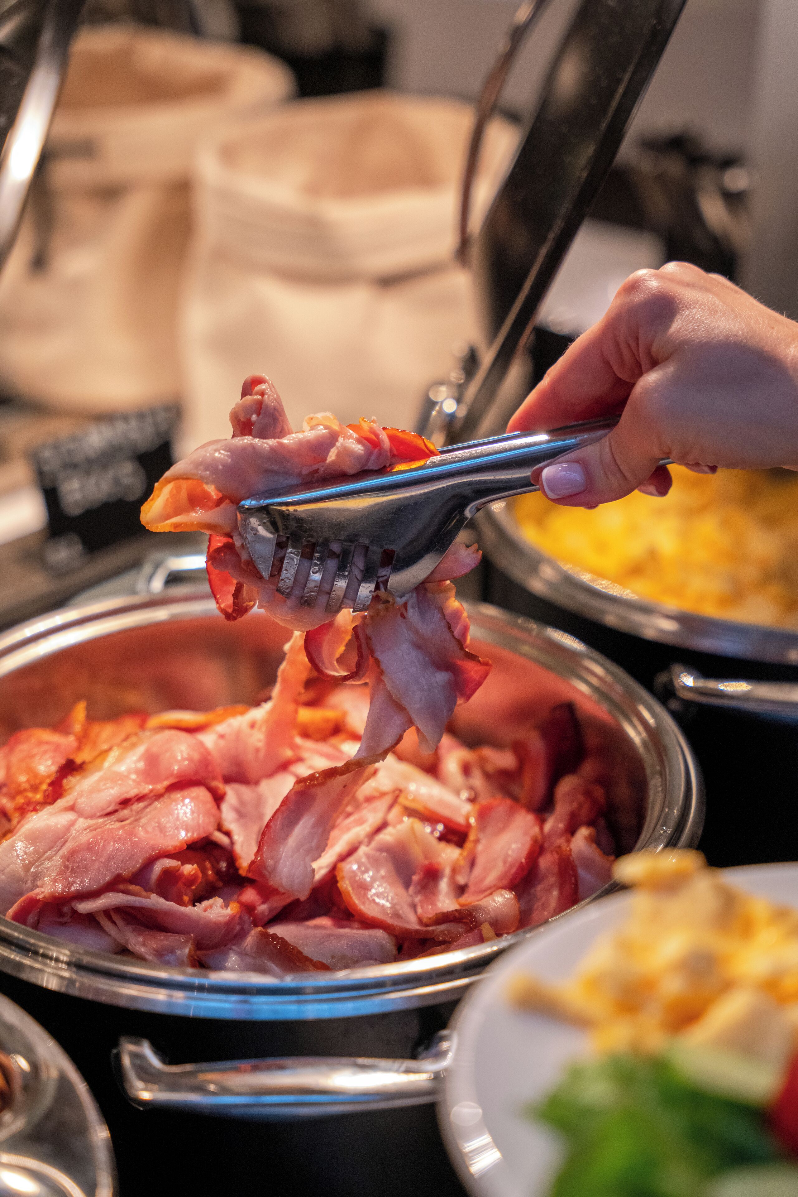 A buffet with various food items, including sliced ham and a dish with a yellow topping.