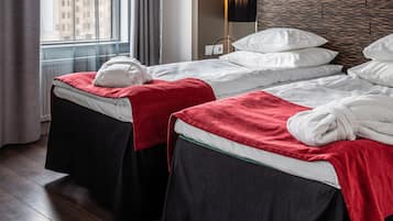 Habitación de hotel con dos camas, un ventanal con cortinas, diseño de pared moderno y vistas a la ciudad.