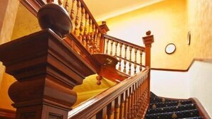 A wooden staircase with a balustrade, leading to a landing with a round light fixture. - Heriott Park Guest House (Edinburgh)