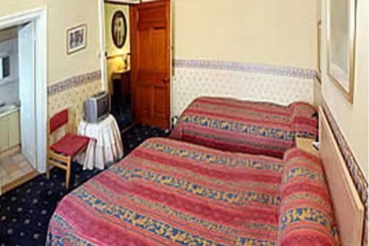 Quarto com duas camas, uma mesinha e uma cadeira.