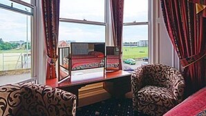 A bedroom with a large window, a bed, a chair, and a desk with a mirror. - Heriott Park Guest House (Edinburgh)