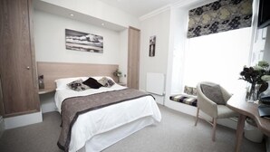 A bedroom with a bed, bedside table, chair, and a window with a view. - Plas Hyfryd Hotel (Narberth)