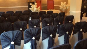 Rows of chairs with black sashes and white chairs, a wooden wall, and a mirror on a stand. - Plas Hyfryd Hotel (Narberth)