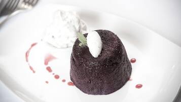 A dessert consisting of a chocolate lava cake with a scoop of ice cream and a mint leaf garnish.