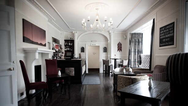 A spacious hotel lobby with a grand chandelier, a bar area, and a seating area with a fireplace. - Plas Hyfryd Hotel (Narberth)