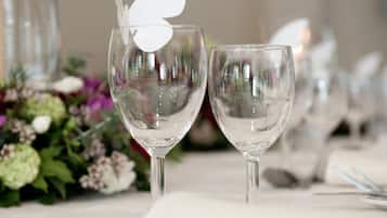 A table set with wine glasses and cutlery, with a decorative white bird on one glass.