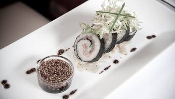 A sushi dish with a side of sesame seeds on a white plate.