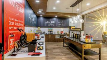 A modern kitchen area with waffle-making equipment, a coffee station, and a seating area with a view.
