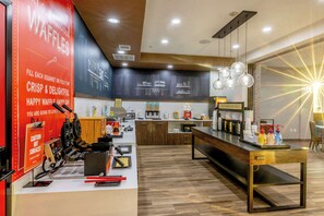 A modern kitchen area with waffle-making equipment, a coffee station, and a seating area with a view.