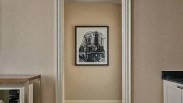 A hallway with a framed black and white photograph on the wall, patterned carpet, and a wooden cabinet with a marble countertop.