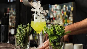 Een bartender bereidt een drankje toe met ijs en kruiden.