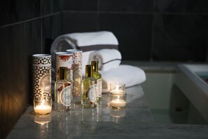 A bathroom with a marble countertop, candles, and bottles of toiletries.