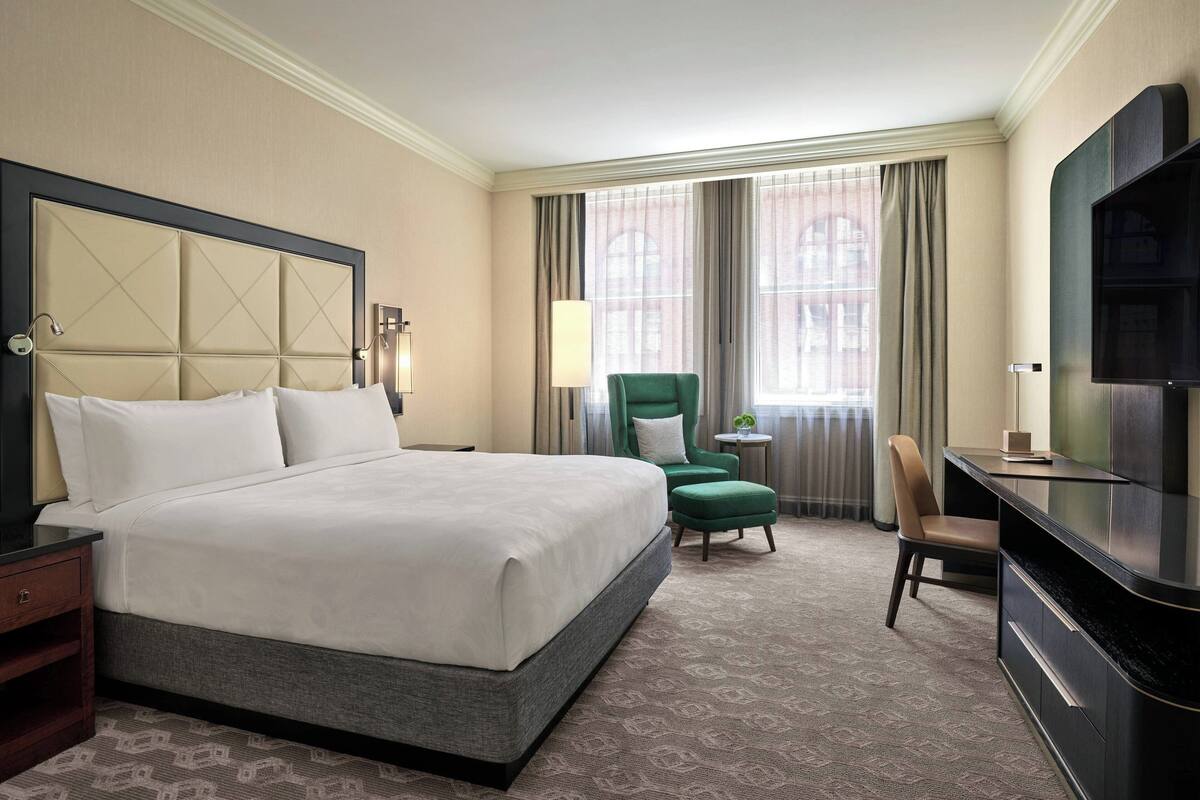 Une chambre d’hôtel avec un grand lit, un bureau, une télévision et une chaise.