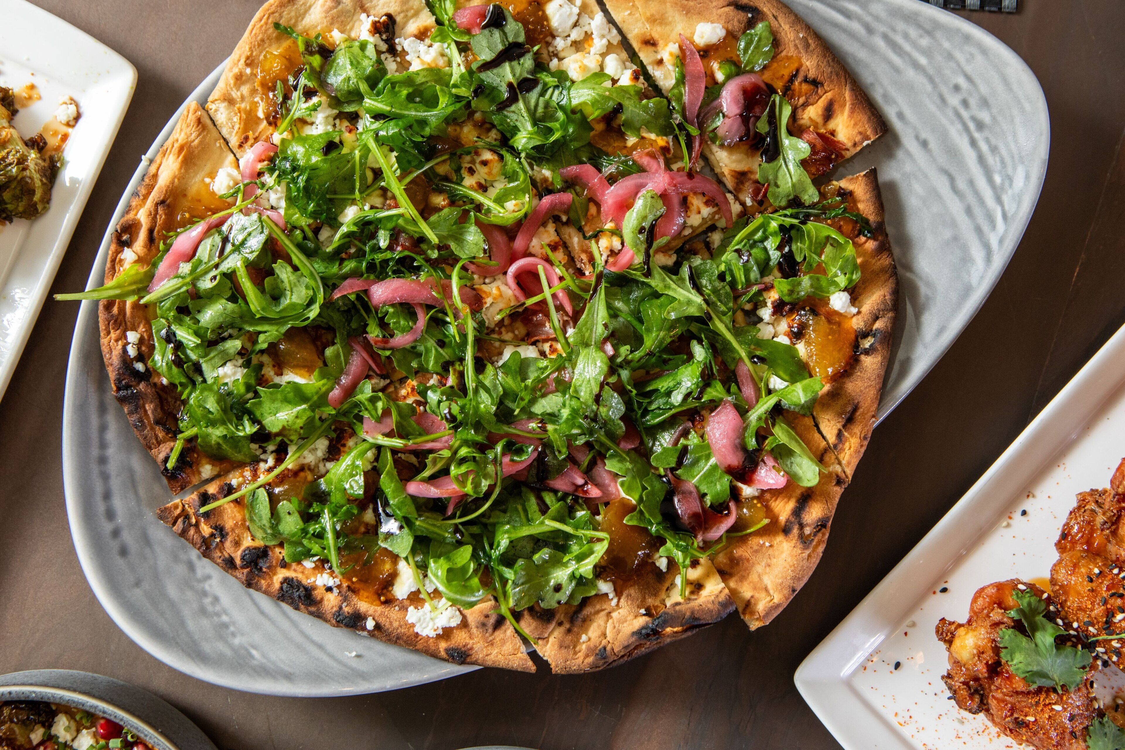 Une pizza garnie de divers ingrédients, servie sur une assiette blanche.