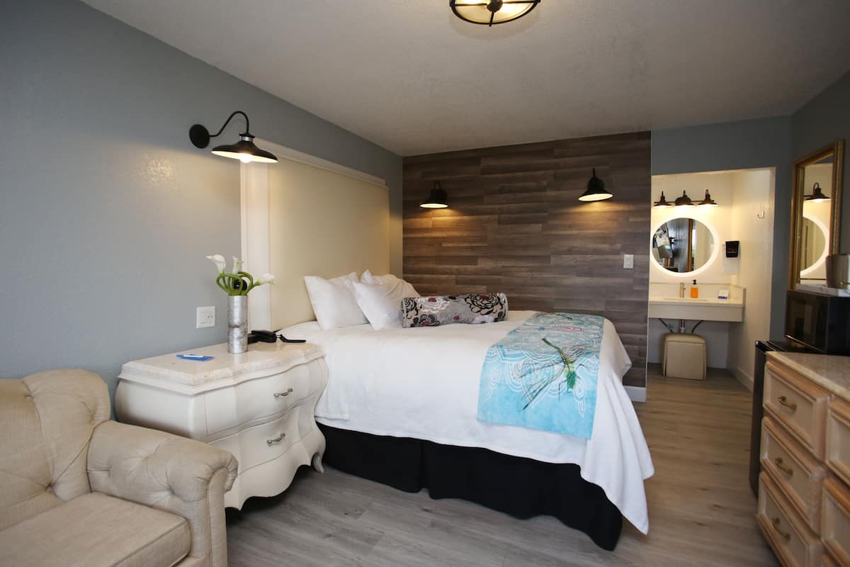 A bedroom with a bed, bedside tables, a dresser, a mirror, and a vanity with a sink.