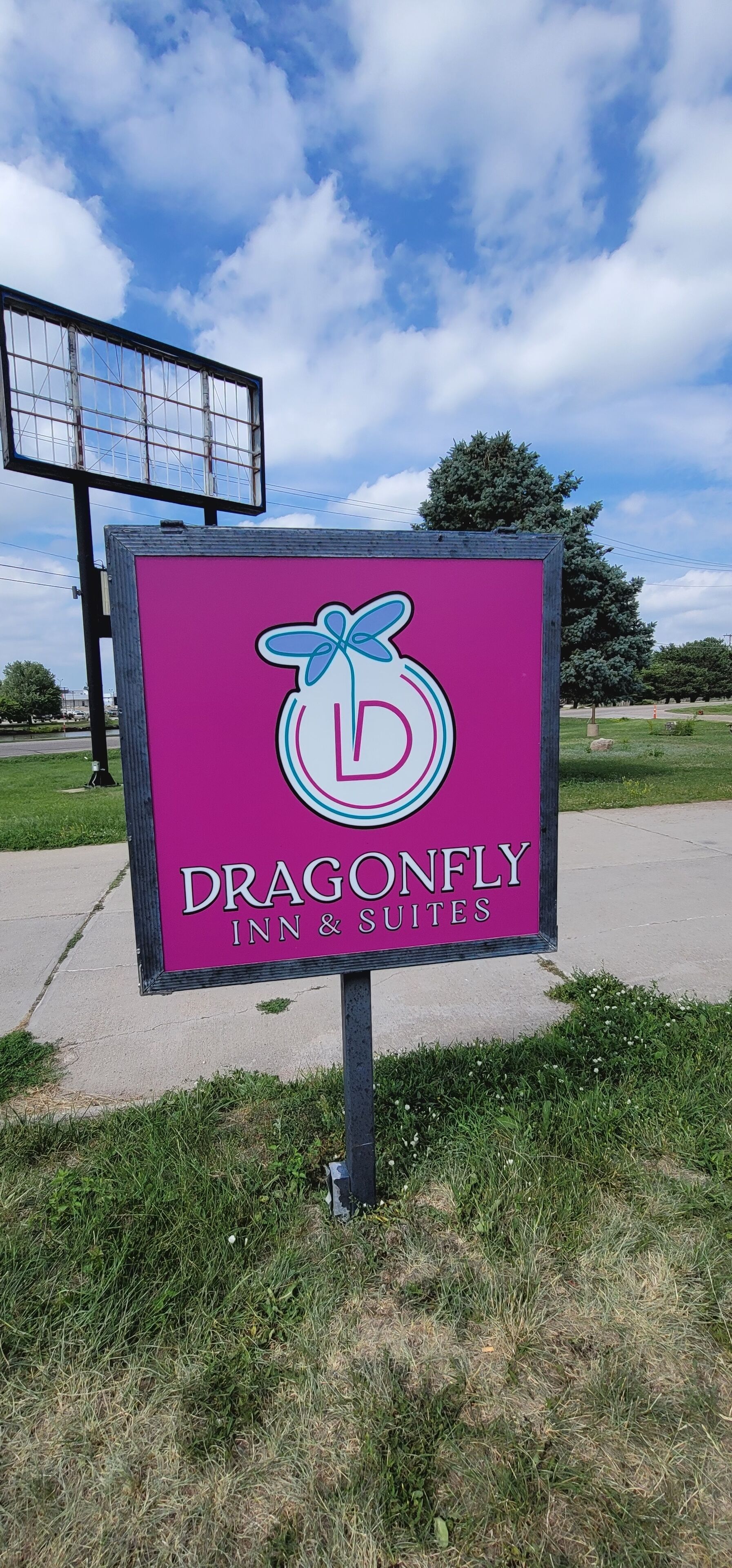 A sign for Dragonfly Inn & Suites with a logo featuring a stylized dragonfly and a letter 'D'.