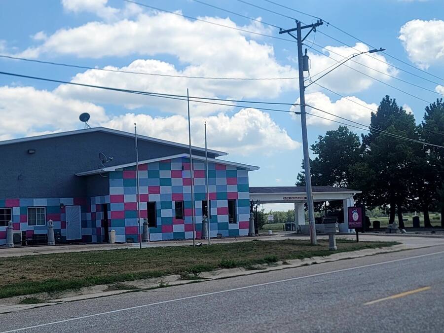 Un edificio de fachada colorida, una gasolinera al fondo y un cielo despejado.