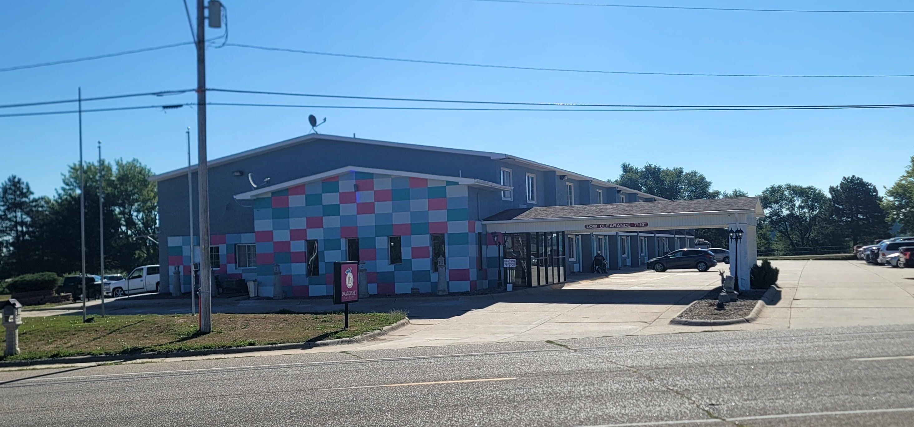 A building with a colorful facade, a covered parking area, and a sign indicating low clearance.
