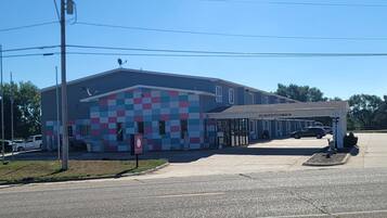 A building with a colorful facade, a covered parking area, and a sign indicating low clearance.