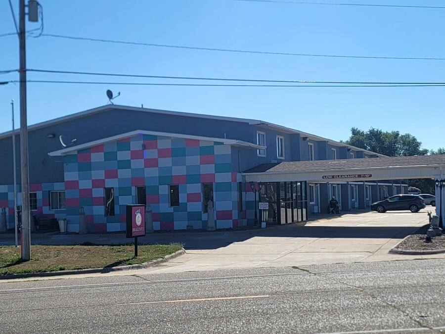 A building with a colorful facade, a covered parking area, and a sign indicating low clearance.