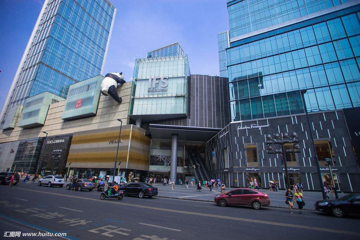A modern urban street with high-rise buildings, a prominent IFSC sign, and a busy pedestrian area.