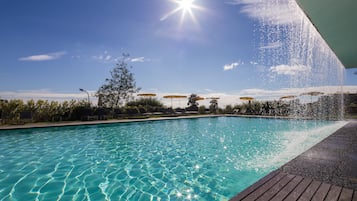 Una piscina techada, una piscina al aire libre, sombrillas