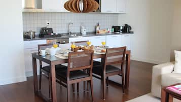 Cozinha moderna com armários brancos, uma mesa de jantar posta para quatro pessoas e uma cafeteira.