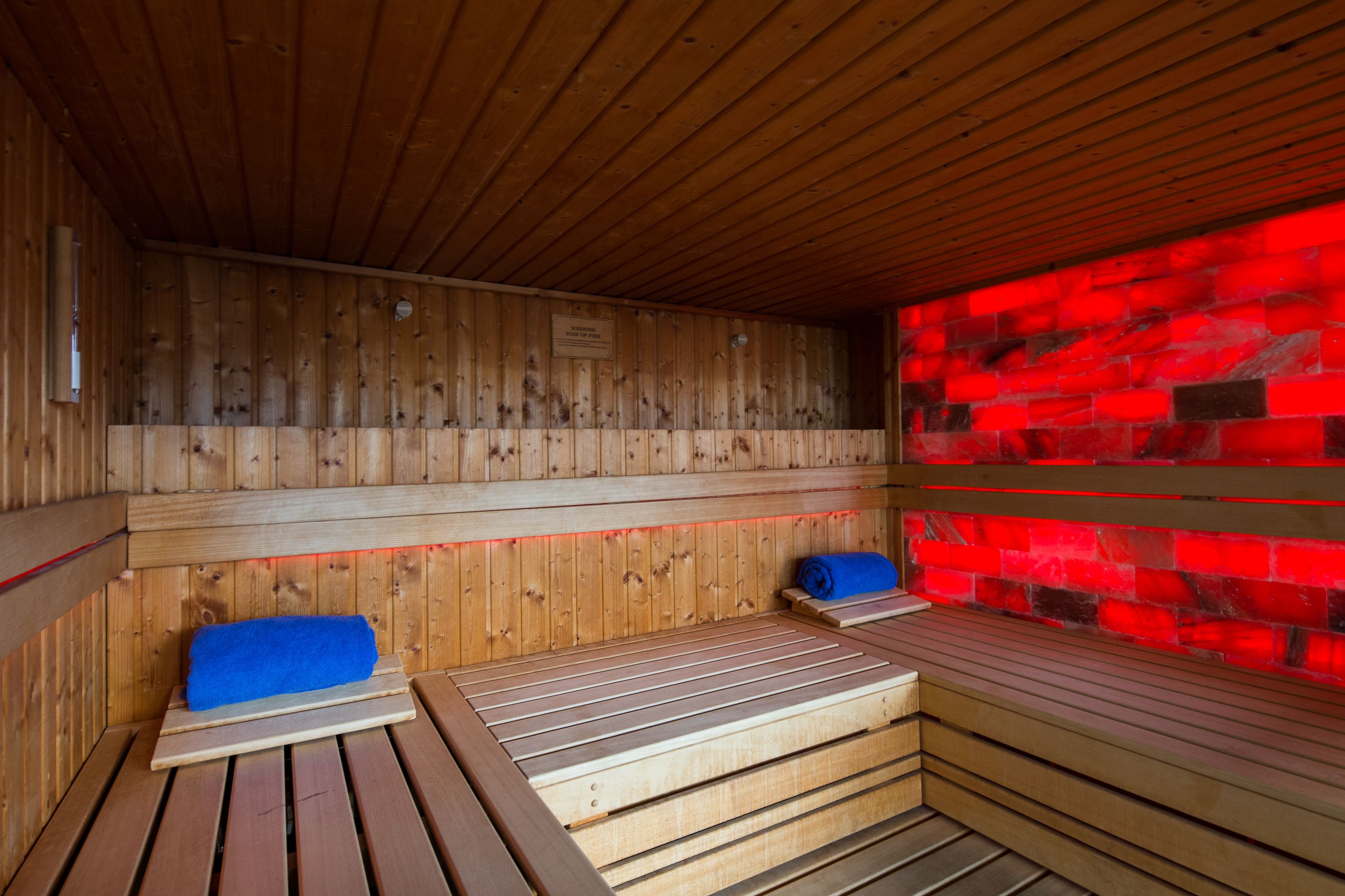 Un sauna en bois, avec des bancs et un mur recouvert de tuiles rouges.
