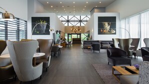 Un vestíbulo espacioso con muebles modernos, amplias ventanas y obras de arte en las paredes.