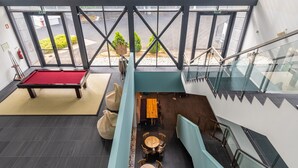 Un espacio interior moderno con mesa de billar, zona de estar y una escalera.