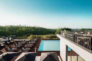 A rooftop pool area with lounge chairs and umbrellas, surrounded by lush greenery and a clear sky. - Monchique Resort & Spa (Monchique)