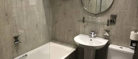 Un baño moderno con una bañera, un lavamanos y un inodoro.