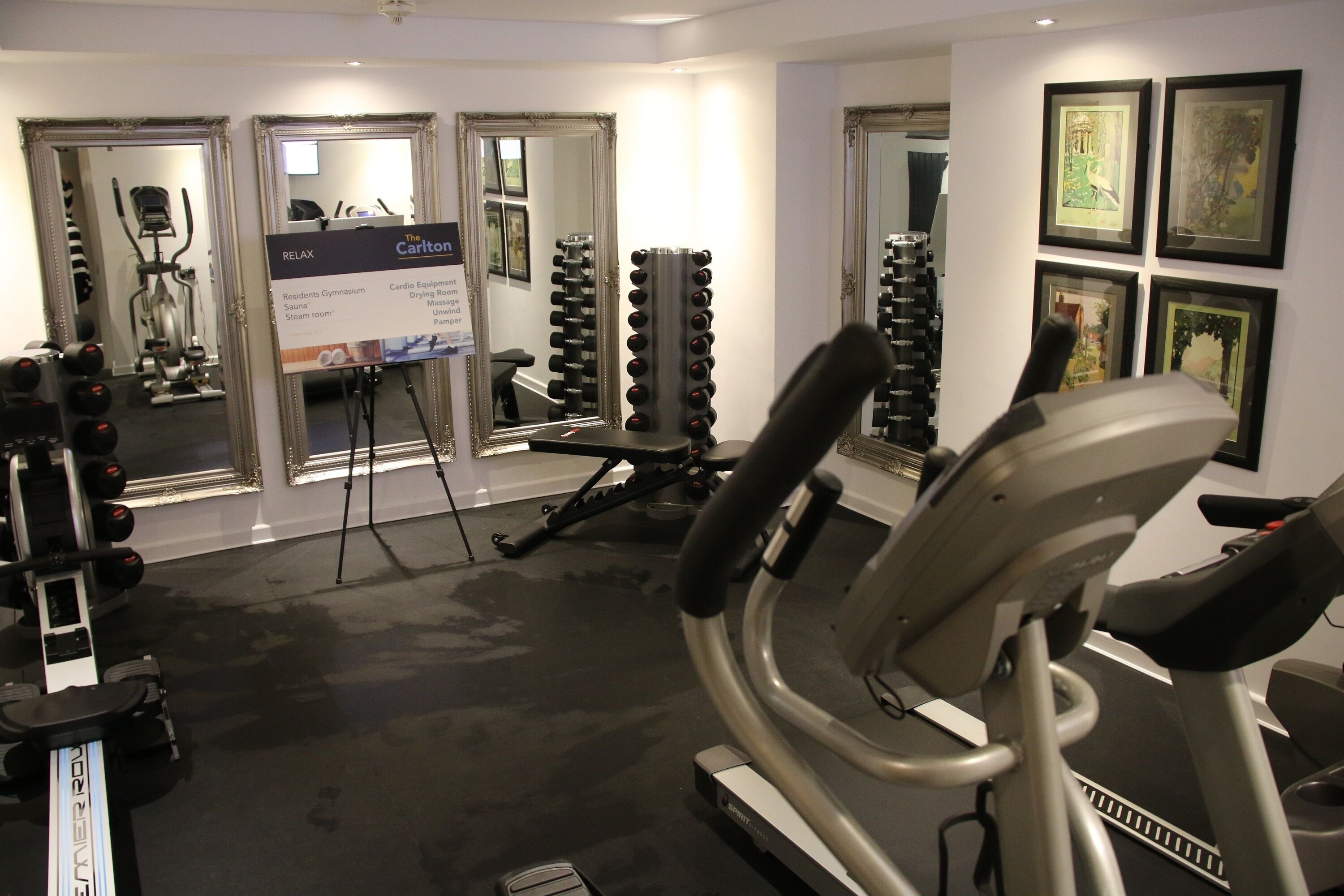 Een sportschool met cardioapparatuur, krachtapparaten en een loopband.