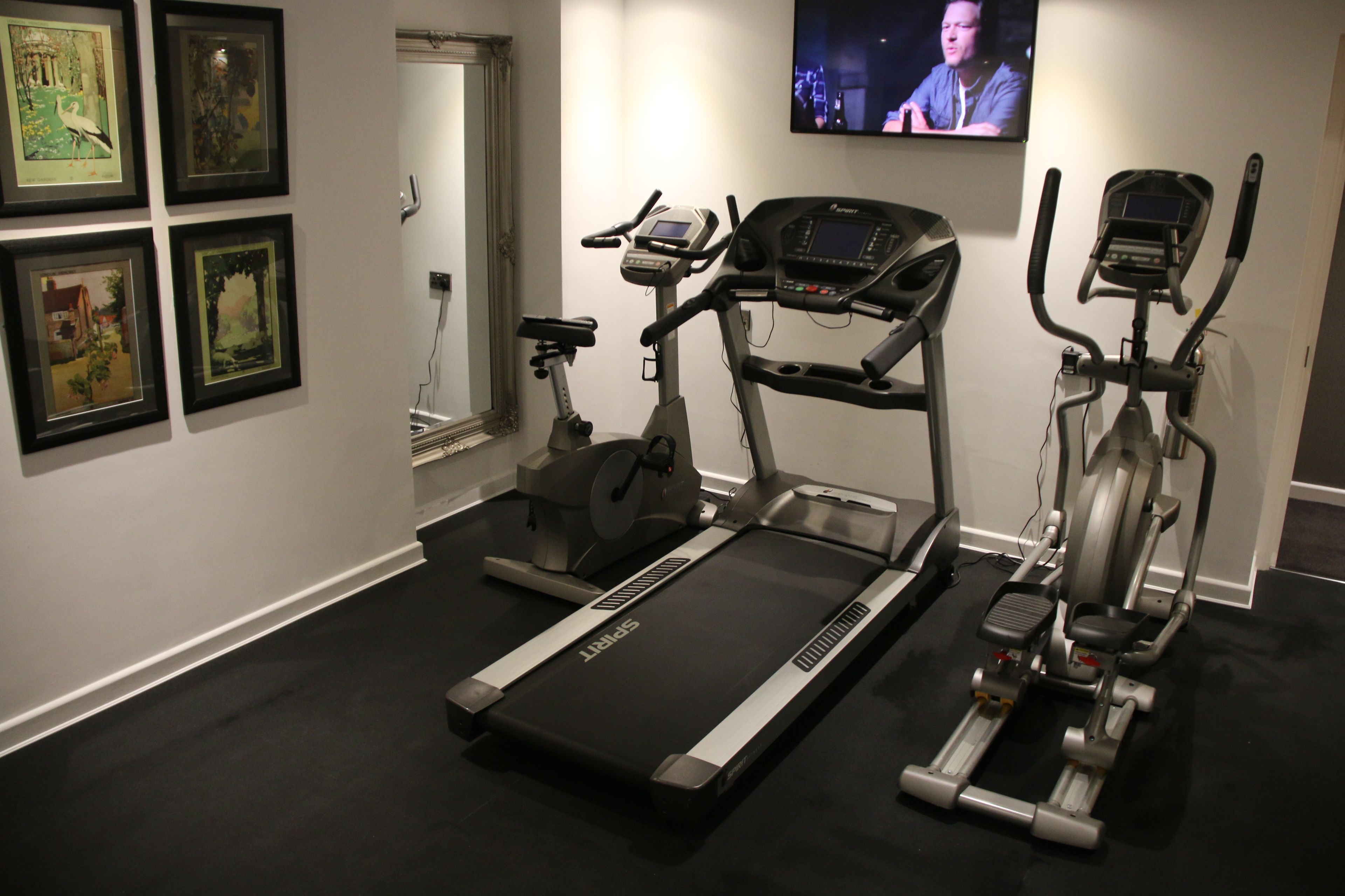 A home gym with a treadmill, elliptical, and stationary bike.