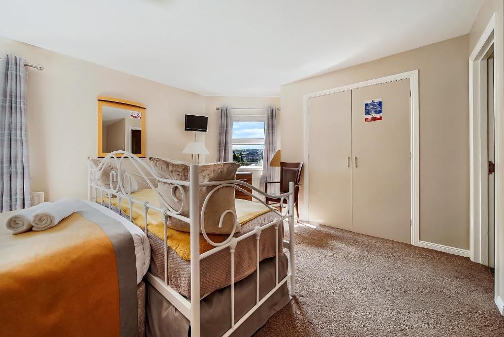 A hotel room with a bed, a desk, a chair, a television, and a wardrobe.