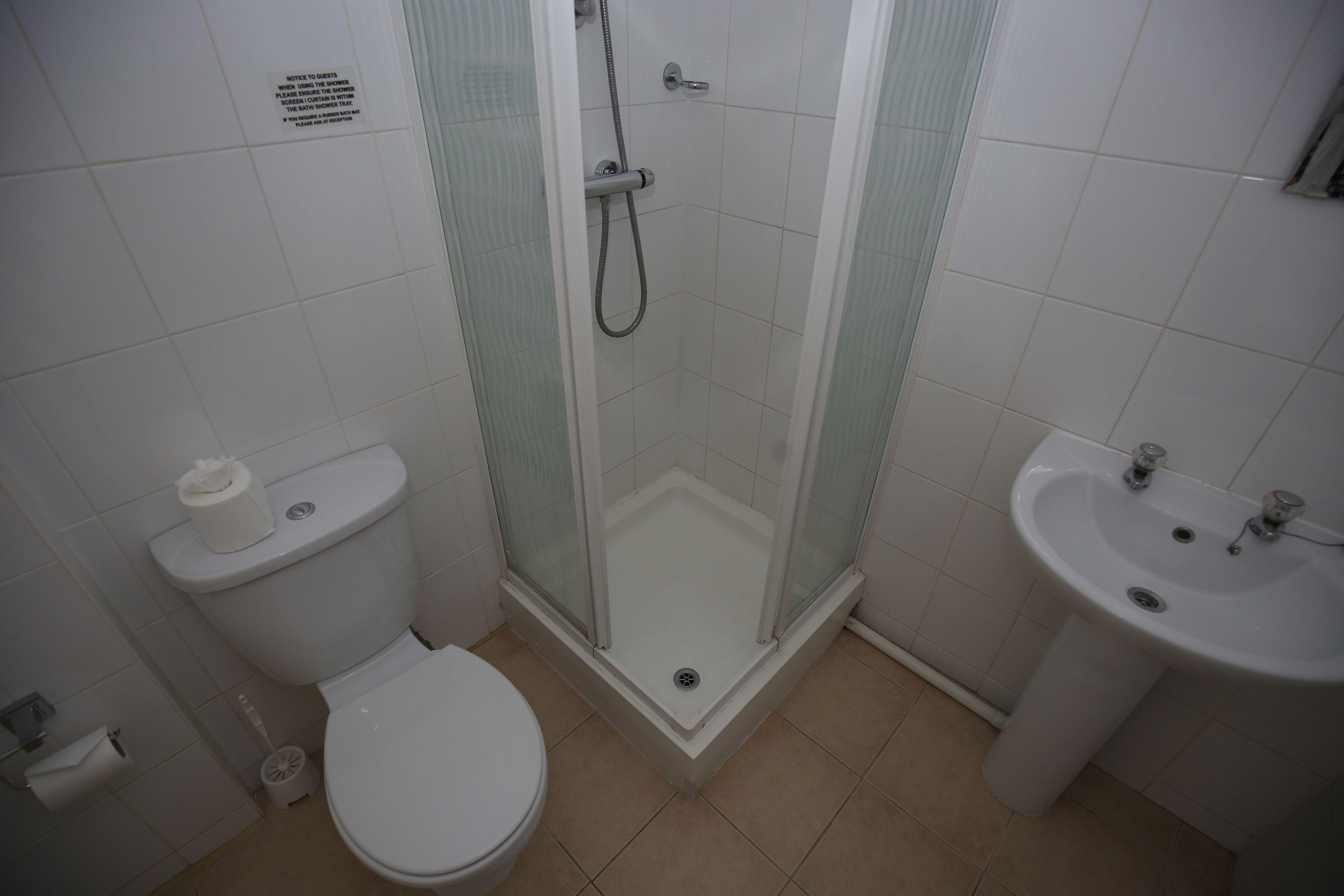 A bathroom with a toilet, a glass-enclosed shower, and a sink.