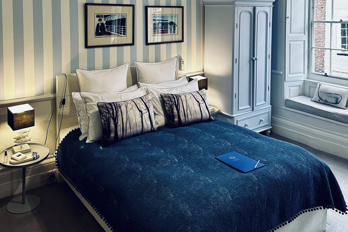 Un dormitorio con cama, armario, mesita de noche, escritorio y ventana con vistas.