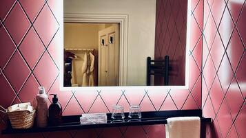 A bathroom with a large mirror, a sink, and a shelf with toiletries.