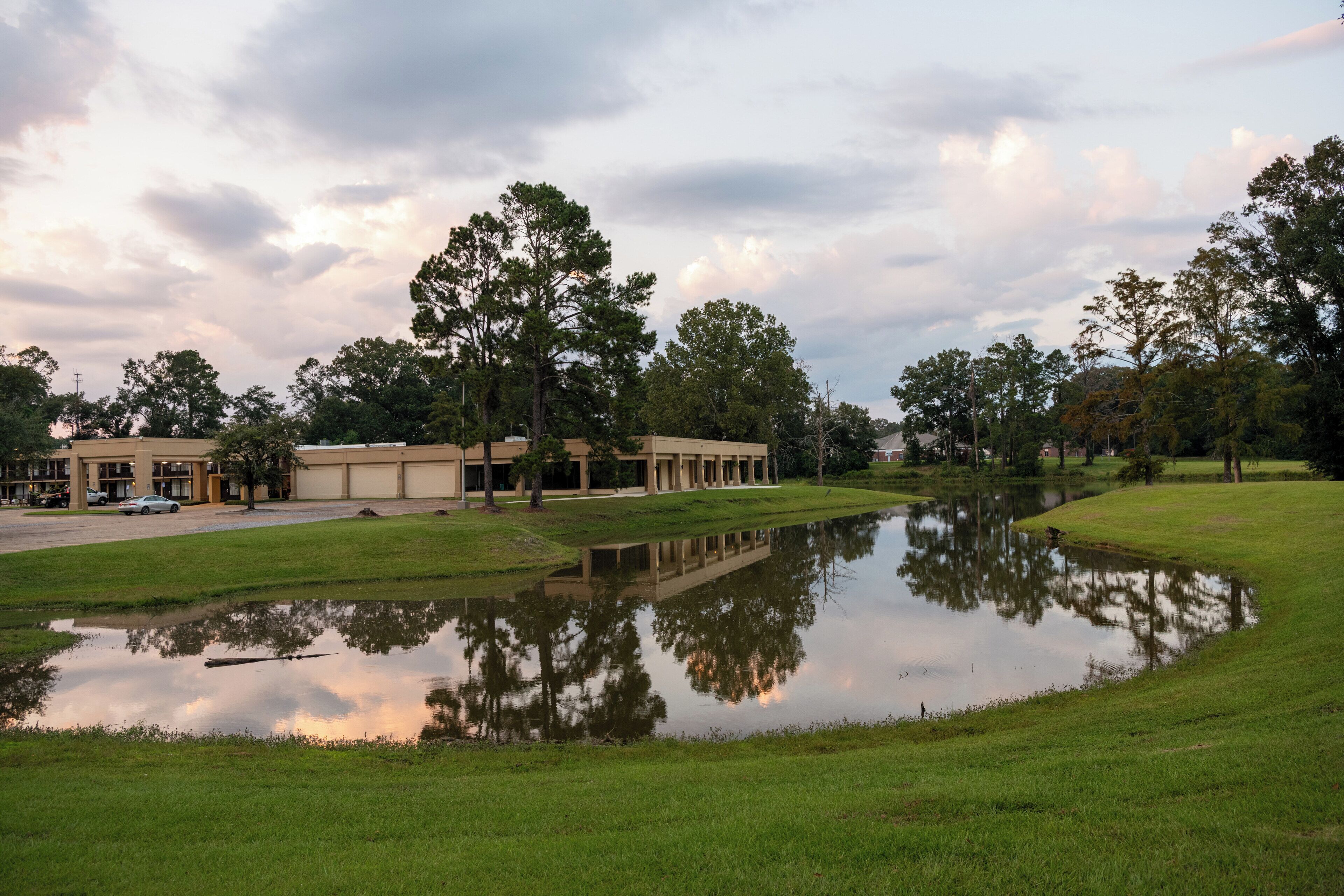A building with a large lawn and a pond.