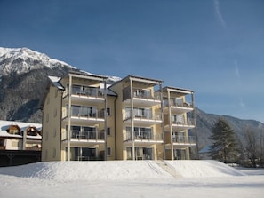 Un hôtel à plusieurs étages, doté de balcons, qui se dresse sur fond de montagnes enneigées.