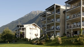 A multi-story hotel with balconies, situated in a mountainous area with a clear sky. - Appartements De Luxe Schluga (Hermagor-Pressegger See)