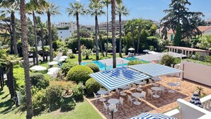 Un espace piscine agrémenté de parasols, de chaises et de palmiers.