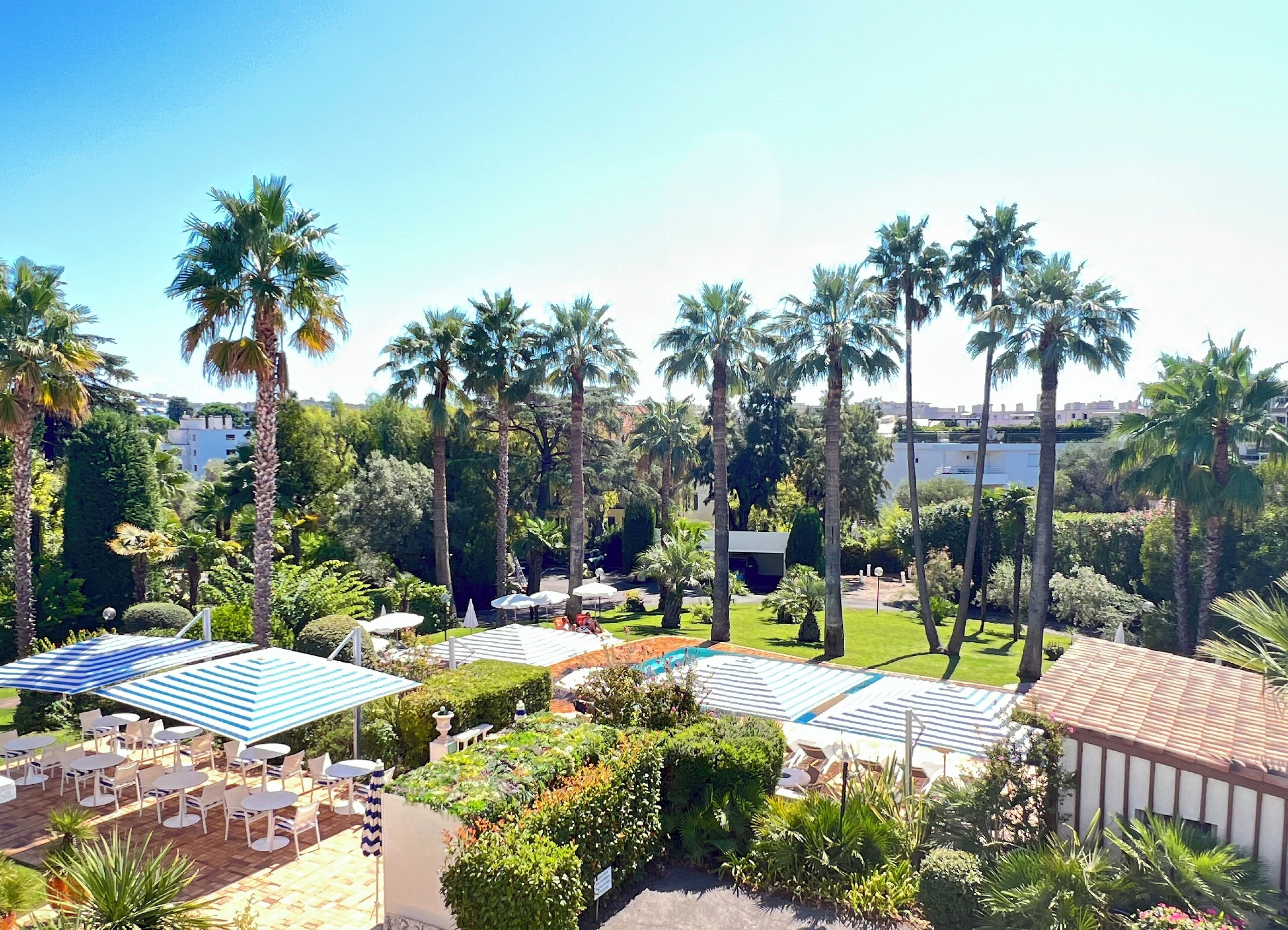 Un resort con asientos al aire libre, palmeras y una zona de piscina.