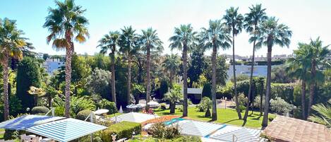 Un resort con asientos al aire libre, palmeras y una zona de piscina.