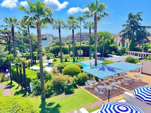 A resort with a swimming pool, palm trees, and outdoor seating areas. - Hôtel des Mimosas (Antibes)