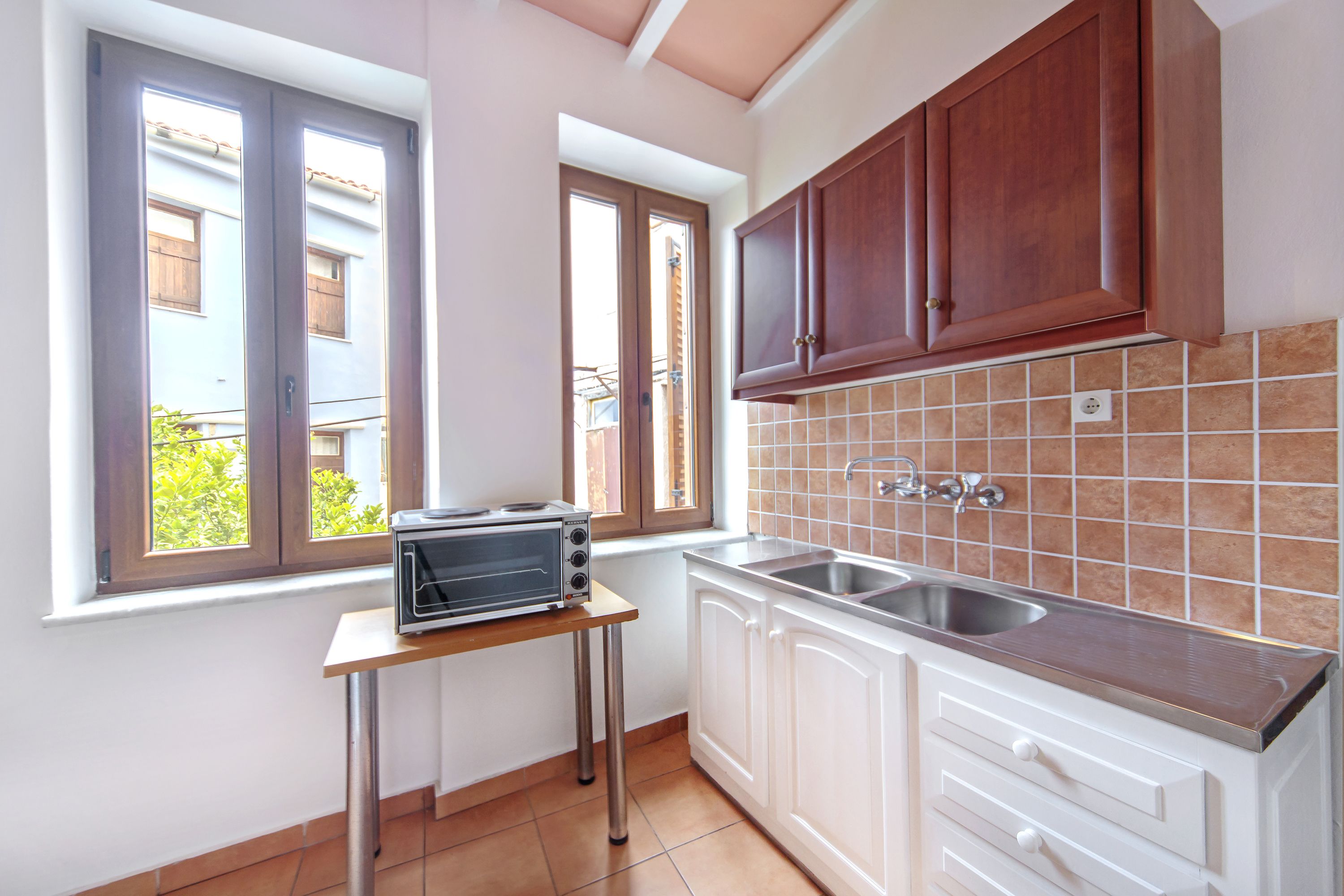 A compact kitchen with a microwave, sink, and wooden cabinets.