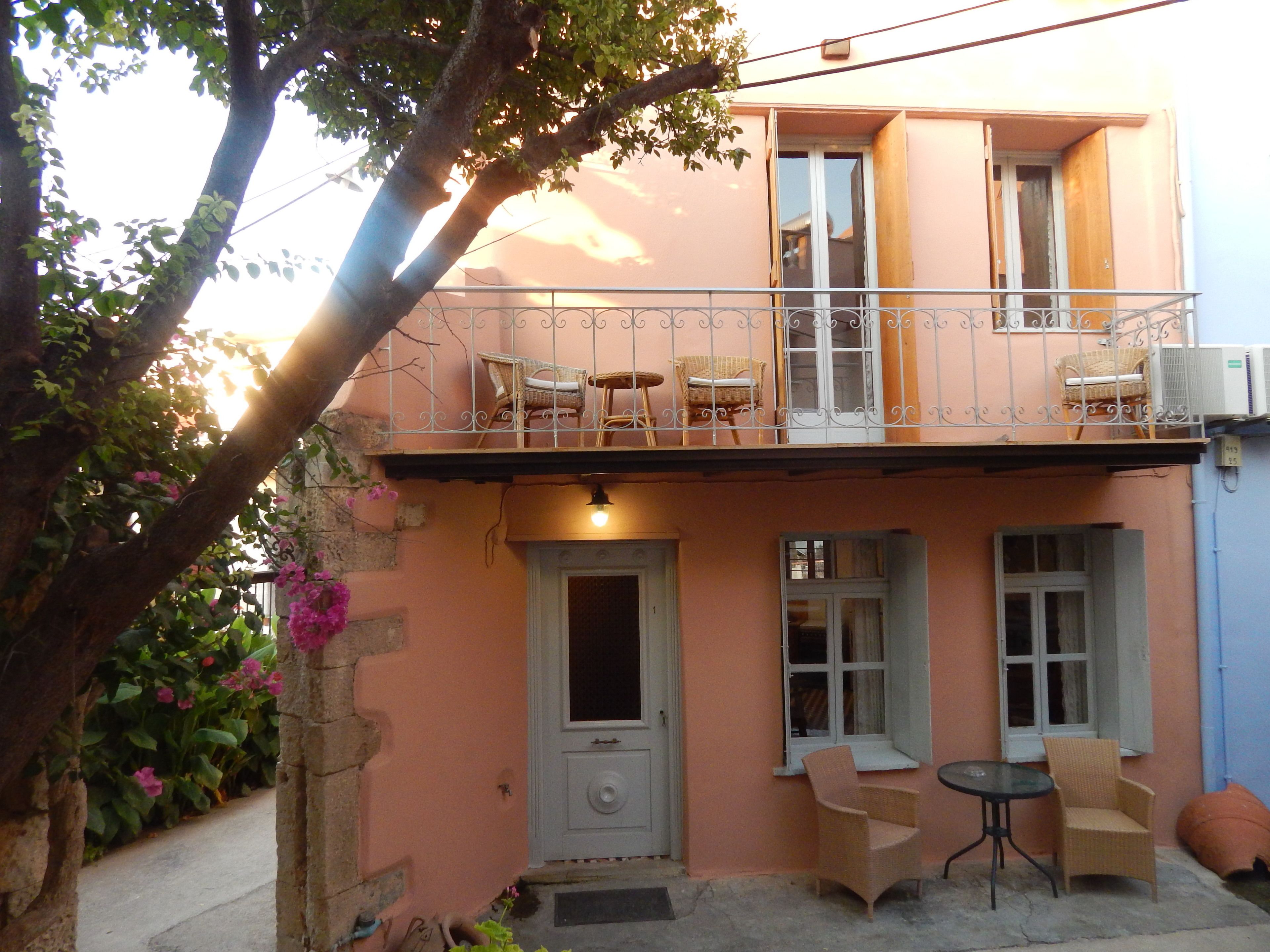 A two-story building with a balcony, a door, and two windows.