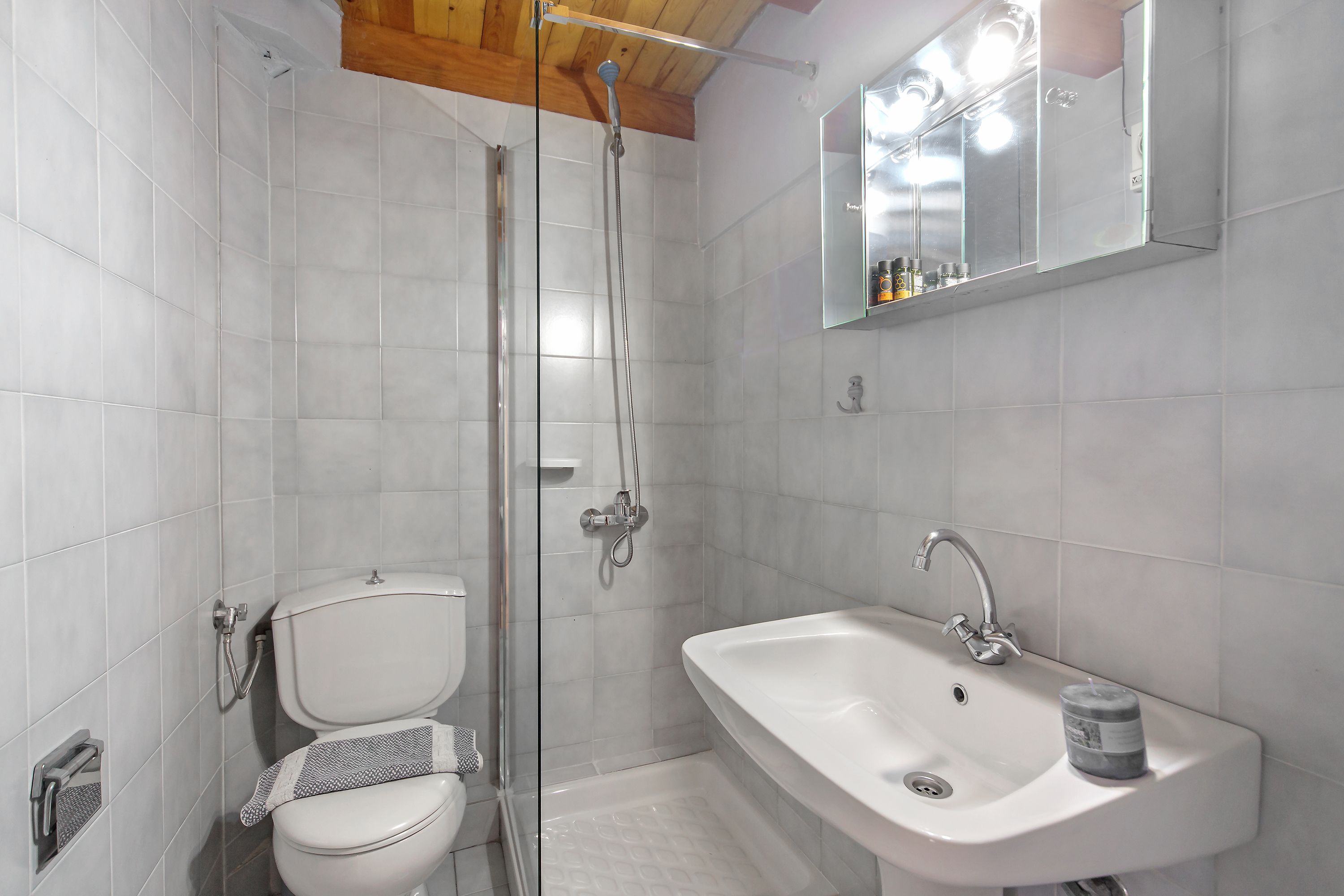 A bathroom with a toilet, shower, sink, and a mirror above the sink.